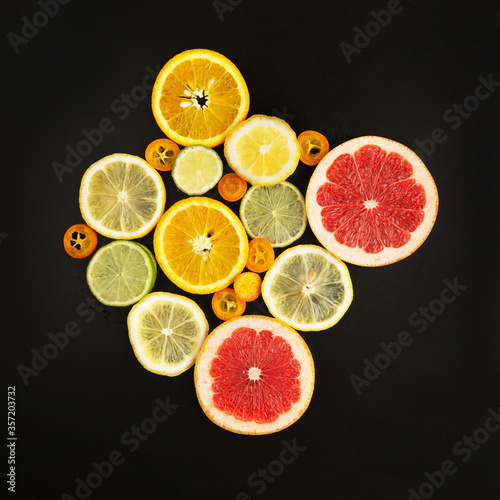 Fototapeta Naklejka Na Ścianę i Meble -  Composition of fresh cut citrus fruits slices on abstract black background