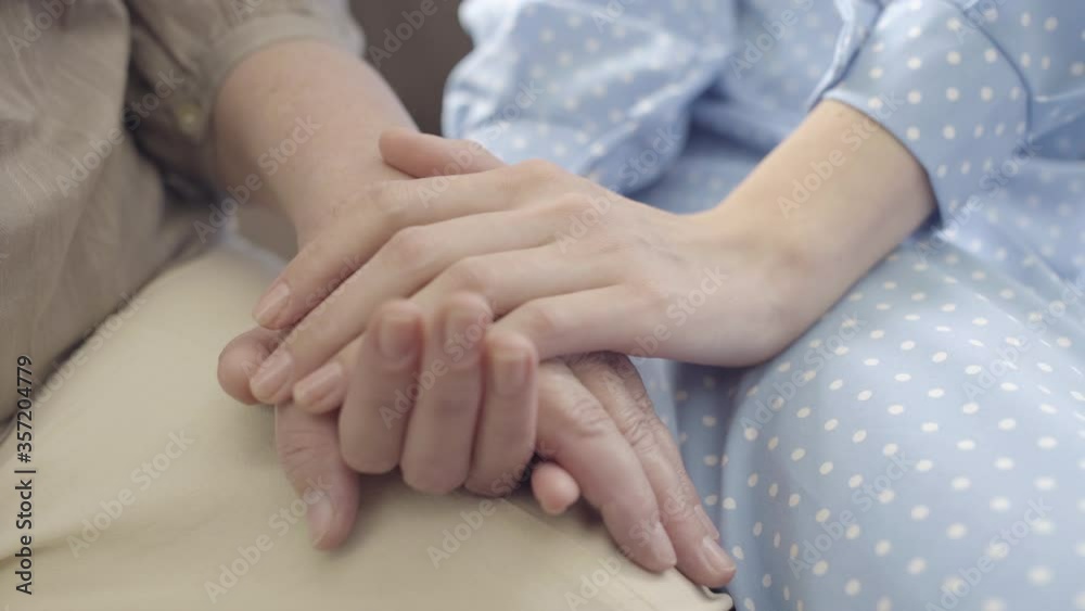 Female holding old mother's hand, elderly care in nursing home, family support Female holding old mother's hand, elderly care in nursing home, family support
