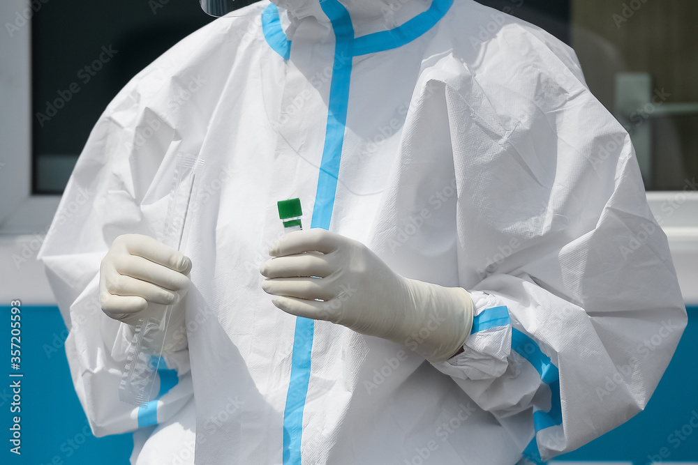 Unrecognizable people wearing protective suit handles a pharyngeal exudate/ swab collection kit for the coronavirus. Test tube for taking OP NP patient specimen sample, PCR DNA testing