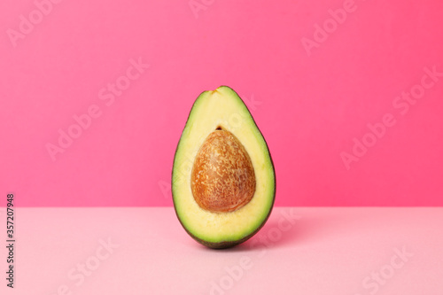 Ripe fresh avocado on pink background, space for text