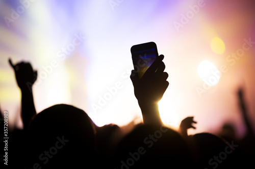 smartphone in the hand of a fan shooting a video at a concert of a favorite group.