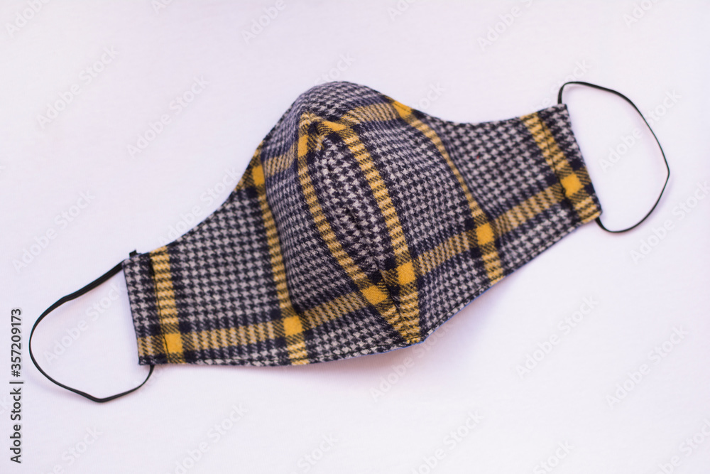 Fashionable protective mask made of plaid fabric, isolated on white background. Covid-19 pandemic protection. Fashionable protective mask made of plaid fabric, isolated on white background. Covid-19 pandemic protection.
