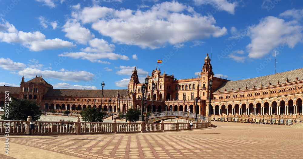 architecture of the Square of Spain in Seville, with the buildings, bridges and a blue sky with clouds in the background - empty landscape for a postcard wallpaper