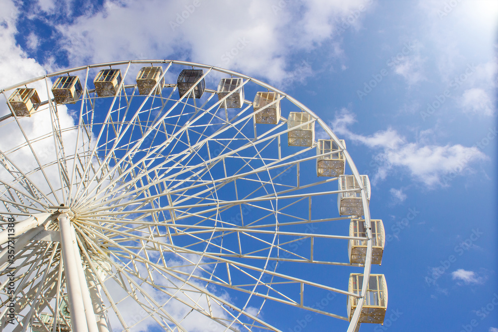 Ferris wheel on the background of blue sky and clouds