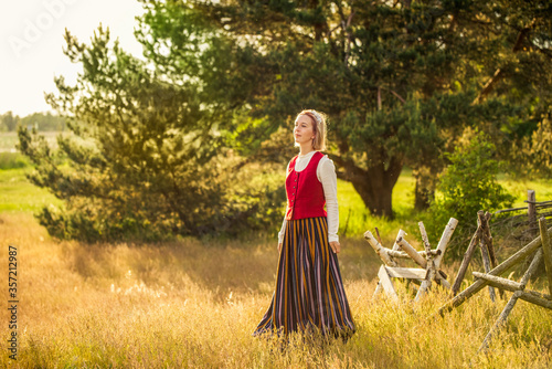 Latvian woman in traditional clothing in field.