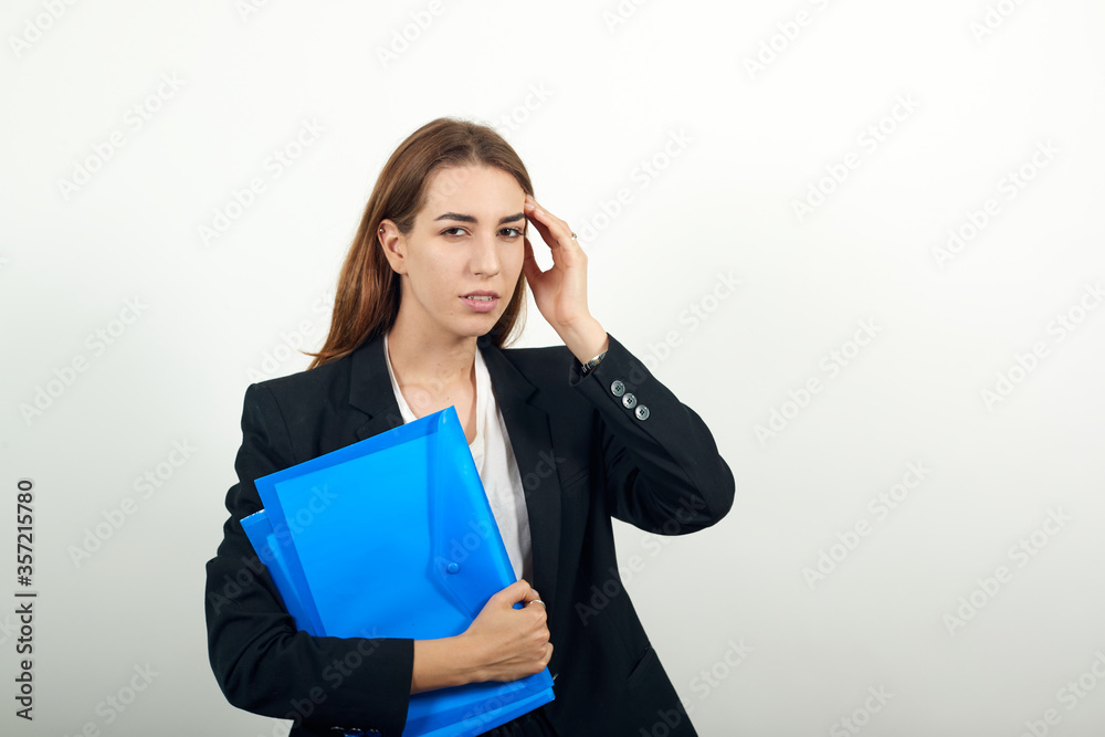Stress or a headache grimacing in pain holds the back of her neck indicating location. Fatigue during workaholism labor. Young attractive woman with brown hair in light t-shirt and black jacket Stress or a headache grimacing in pain holds the back of her neck indicating location. Fatigue during workaholism labor. Young attractive woman with brown hair in light t-shirt and black jacket