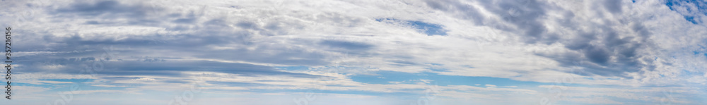 Wide panorama with white and gray clouds on a blue sky