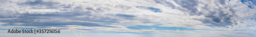 Wide panorama with white and gray clouds on a blue sky