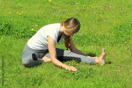 Young woman of European appearance does yoga in summer nature photo