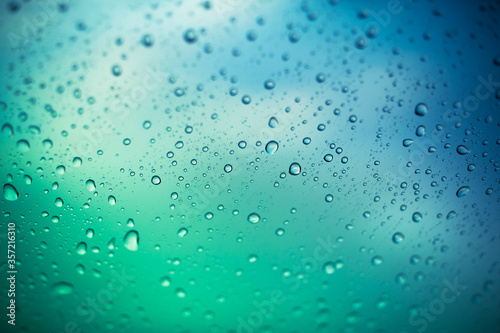 water drops on glass window  green and blue background