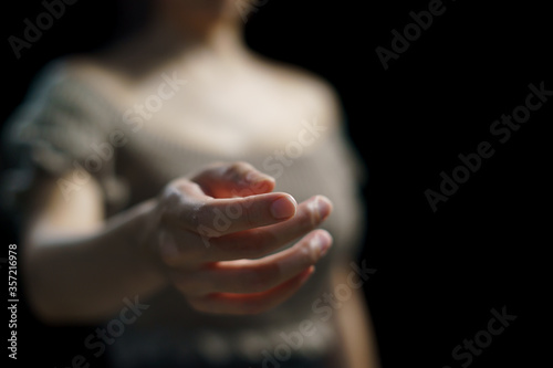 Woman open empty hand on black background.