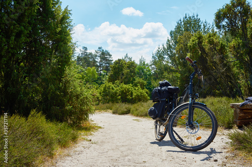 Trekking bike loaded with panniers on a sandy path through the heath in northern Germany