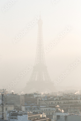 Fototapeta Naklejka Na Ścianę i Meble -  View of buildings and the Eiffel Tower in the fog / cloud of pollution during winter. December 30th, 2016. Paris, France.