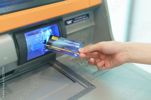 Woman hand inserting a credit card, into bank machine to withdraw money at Automated Teller Machine( ATM ).