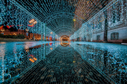 blue chhirstmas lights tunnel reflected in a puddle photo