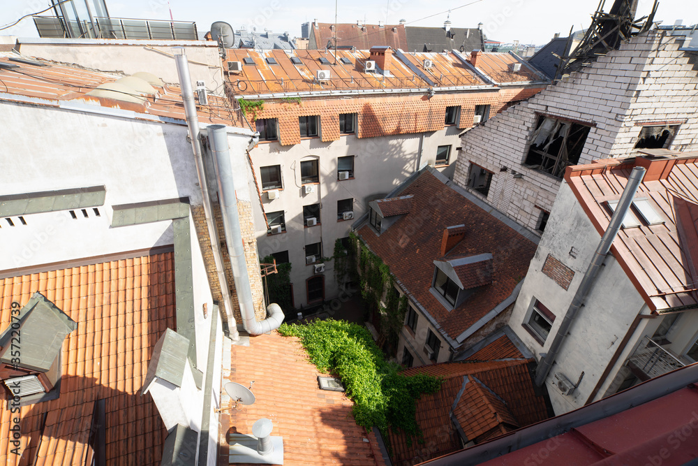 Fototapeta premium Top view of yard in old town of Riga. Old exterior of modern architecture buildings. Red tile roof. Broken window.