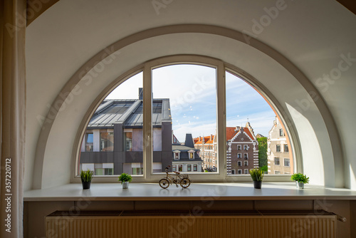 Arch semicircle window. View of old town of Riga, Latvia. Flowers and decorative bicycle on the sill.