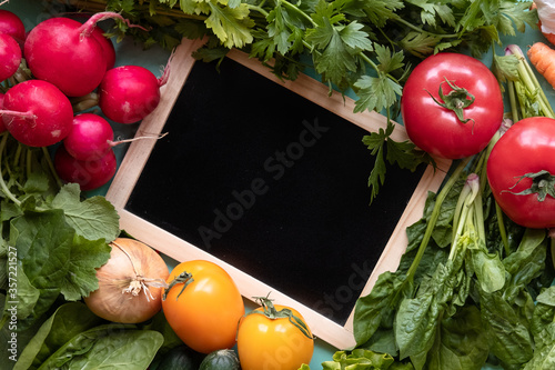 Vegetables around a black desk on blue background. Copy space