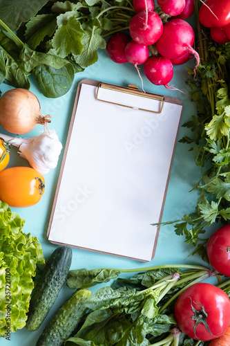 Fresh vegetables around white desk on blue background. Helthy concept. Copy space