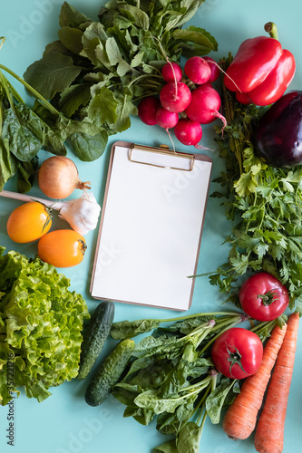 Fresh vegetables around white desk on blue background. Helthy concept. Place  for text