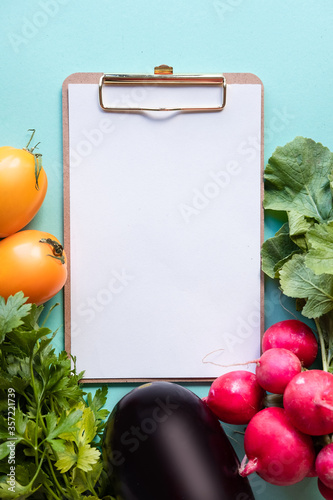 Helthy concept. Fresh vegetables around white desk on blue background. Copy space