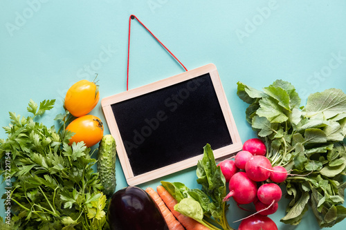 Helthy concept. Fresh vegetables around black desk on blue background. Copy space