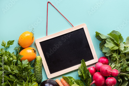 Helthy concept. Fresh vegetables around black desk on blue background.