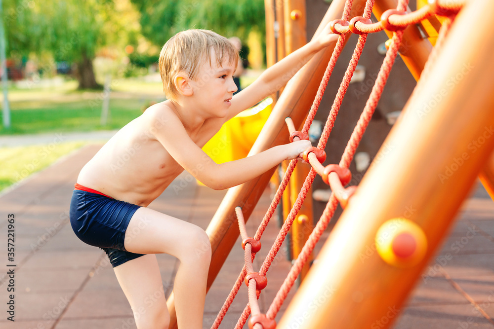 Fototapeta premium Cute boy having fun at the playground on the beach. Summer vacations.