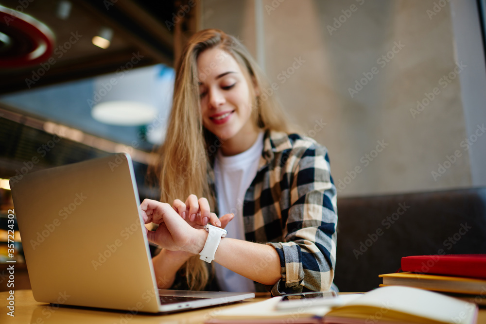 Cheerful female it developer looking at cafeteria window after work on laptop computer Cheerful female it developer looking at cafeteria window after work on laptop computer