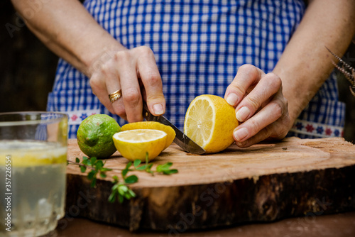 White female hands cutting a lemon on a wooden table.