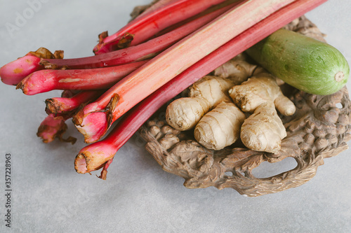 Rhubarb stalks, ginger root and zucchini on a wooden tray. Healthy eating concept.