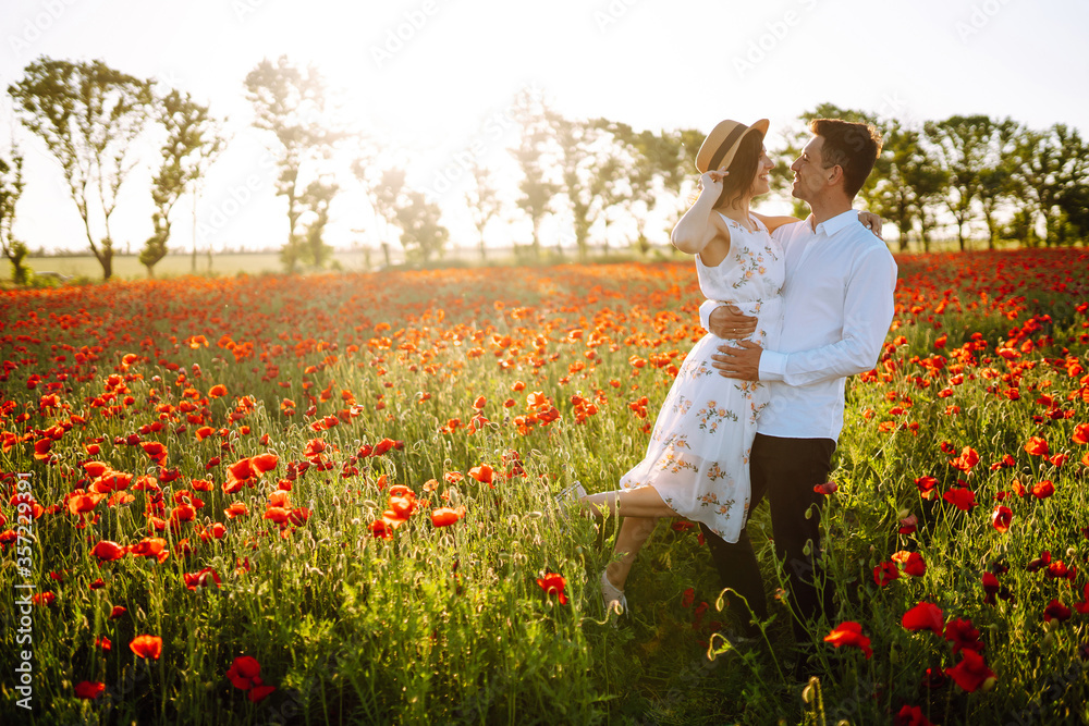 Loving couple in the poppy field. Loving couple hug one another during romantic date in poppy field. Enjoying time together. The concept of youth, love and lifestyle. Loving couple in the poppy field. Loving couple hug one another during romantic date in poppy field. Enjoying time together. The concept of youth, love and lifestyle.