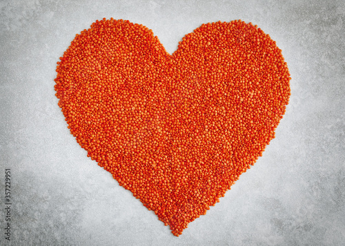 Love heart with red lentils on a light gray background.