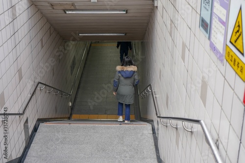 High angle shot of a Korean female going down the stairs to the underground