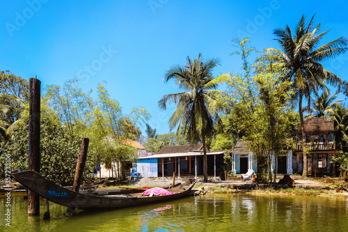 View from the lake of a boat anchored next to a Vietnamese house on the shoresof Dam Thuy Tu river near Hue, Vietnam  photo