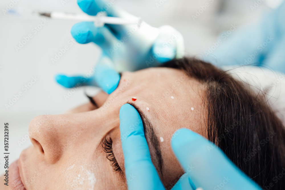 Attractive blond woman is getting a rejuvenating facial injections at beauty clinic. The expert beautician is filling female wrinkles by botulinum. Attractive blond woman is getting a rejuvenating facial injections at beauty clinic. The expert beautician is filling female wrinkles by botulinum.
