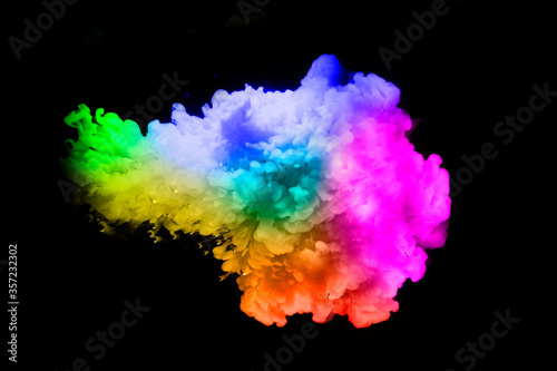 Colorful paint drops from above mixing in water. Ink swirling underwater. on background black