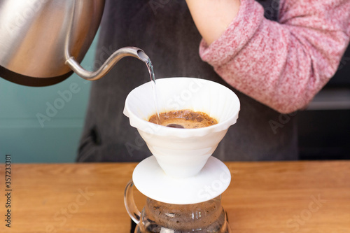 barista makes espresso using a funnel. The process of making coffee in the prover. Spilling coffee through the filter funnel from the kettle.