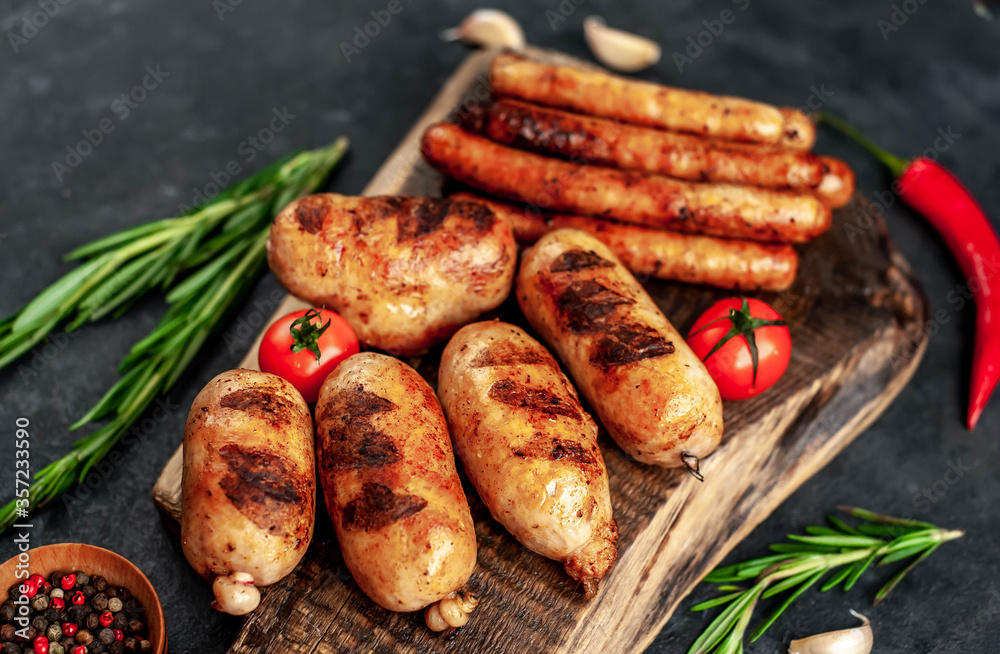 Different grilled sausages with spices and
rosemary, served on a cutting board on a stone background Different grilled sausages with spices and
rosemary, served on a cutting board on a stone background