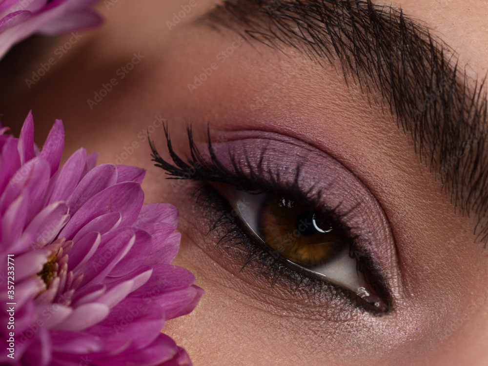 Fototapeta premium Macro shot of woman's beautiful eye with extremely long eyelashes. Sexy view, sensual look. Female eye with long eyelashes. Makeup and Flowers Wreath.