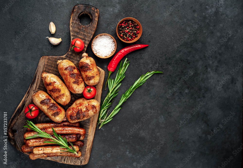 Different grilled sausages with spices and
rosemary, served on a cutting board on a stone background with copy space for your text Different grilled sausages with spices and
rosemary, served on a cutting board on a stone background with copy space for your text