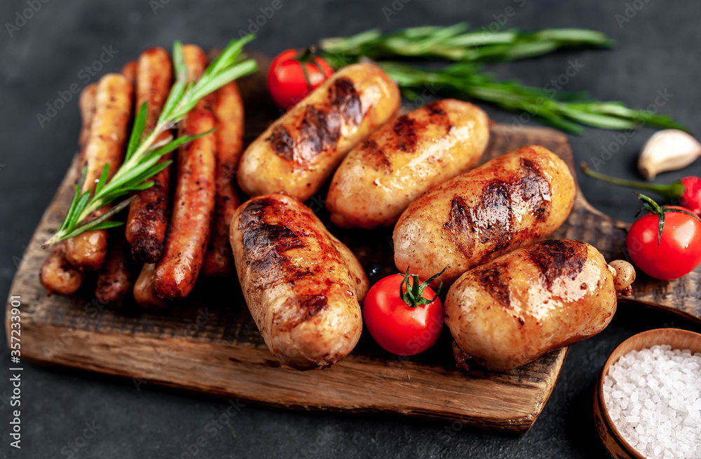 Different grilled sausages with spices and
rosemary, served on a cutting board on a stone background Different grilled sausages with spices and
rosemary, served on a cutting board on a stone background
