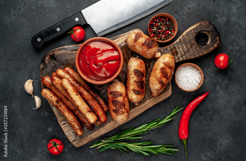 Different grilled sausages with spices and
rosemary, served on a cutting board on a stone background