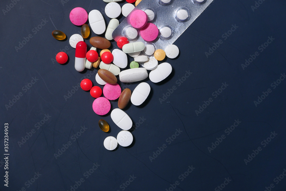 Close up of colorful pills spilling on dray desk 