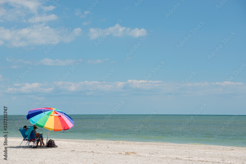 Vacationers Relaxing Under a Colorful Umbrella on the Gulf Coast at Sanibel Island Florida