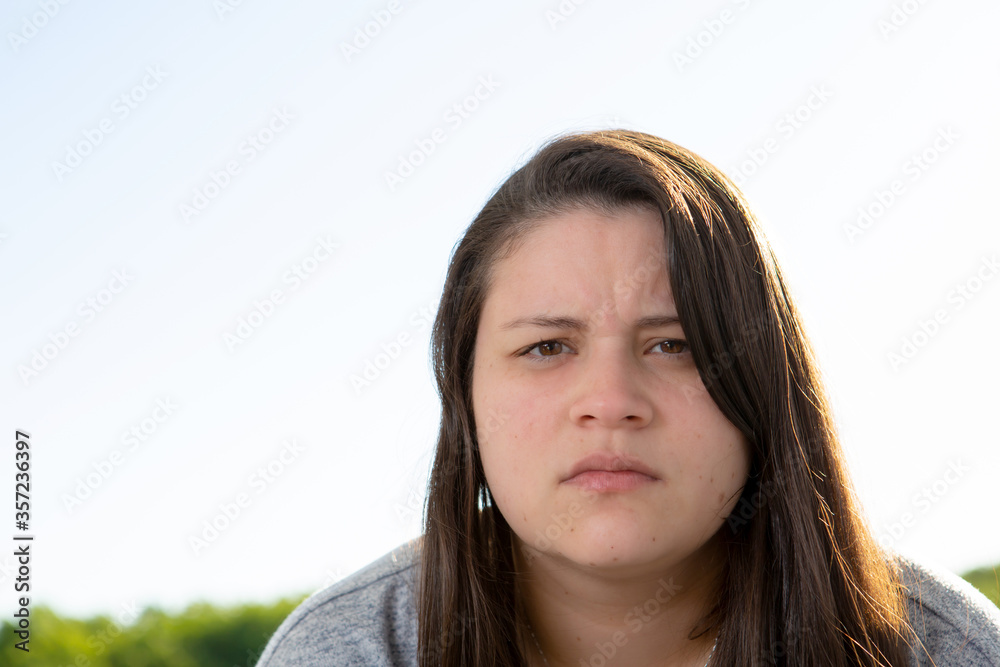 Portrait of a young woman looking at the camera. She is in a balcony and the sunlight falls on her hair. She is serious and looking to the camera. Portrait of a young woman looking at the camera. She is in a balcony and the sunlight falls on her hair. She is serious and looking to the camera.