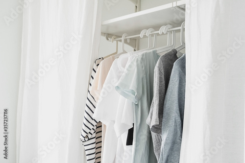 basic women's clothes on a hanger, open wardrobe with textile curtains close-up