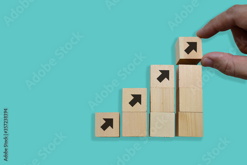 Business concept growth success process, Close up Man hand arranging wood block stacking as step stair on blue background, copy space.