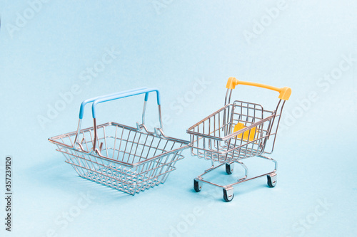 small toy basket and shopping trolley on a blue background, copy space, shopping concept.