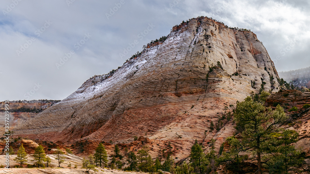 A snow covered mountain in Zion National Park with storm clouds overhead. 
